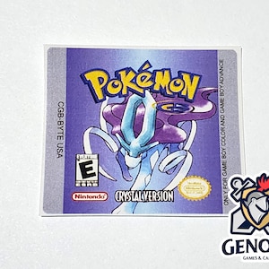 May include: A purple and blue Game Boy Color game cartridge label for Pokemon Crystal Version. The label features a blue and white Pokemon character with purple hair. The label also includes the text "CGB-BYTE USA", "Pokemon", "Crystal Version", and "Nintendo".