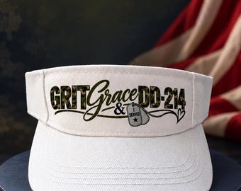 May include: A white visor featuring the text GRIT Grace & DD-214 in a camouflage pattern. The design includes a graphic of two military-style dog tags on a chain, with one tag labeled I SERVED and a small heart icon at the end of the text.