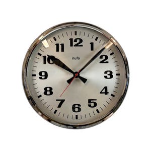 May include: A round wall clock with a silver face and a chrome bezel. The clock has black numerals and hands, with a red second hand. The word "nufa" is printed above the 6 o'clock position.