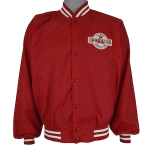 May include: A red varsity jacket featuring a snap-button front closure, long sleeves with ribbed cuffs, and a ribbed collar. The jacket displays an embroidered patch on the upper left chest with the text Alabama Crimson Tide and a mascot graphic.