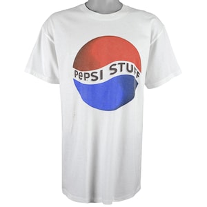 Puede incluir: Camiseta blanca con un logotipo de Pepsi Stuff rojo, blanco y azul.