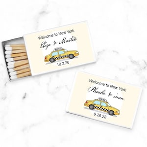 May include: Two yellow and black matchboxes with a cartoon illustration of a New York City taxi cab. The text on the boxes reads "Welcome to New York Eliza & Martin 10.2.26" and "Welcome to New York Phoebe & Ivan 9.26.28".