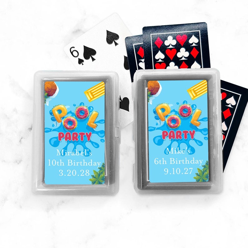 May include: Two personalized playing card decks with a pool party theme. The decks are in clear plastic cases with blue and white labels. The labels feature the text "Pool Party" in red and white letters, along with a birthday message and date. The first deck is for Mirabel's 10th birthday on 3.20.28. The second deck is for Mike's 6th birthday on 9.10.27.