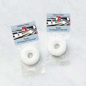May include: Two favor bags with a white candy inside. Each bag has a colorful bowling-themed tag with a name, number, and the text "Thanks for being part of my team!"