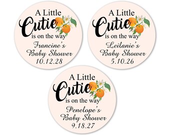 May include: Three round pink and white baby shower stickers with orange blossoms and the text "A Little Cutie is on the way" with the name of the baby shower and the date.