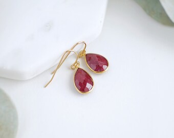 May include: A pair of gold teardrop earrings with red gemstone accents.