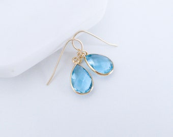 May include: A pair of gold teardrop earrings with light blue gemstone accents.