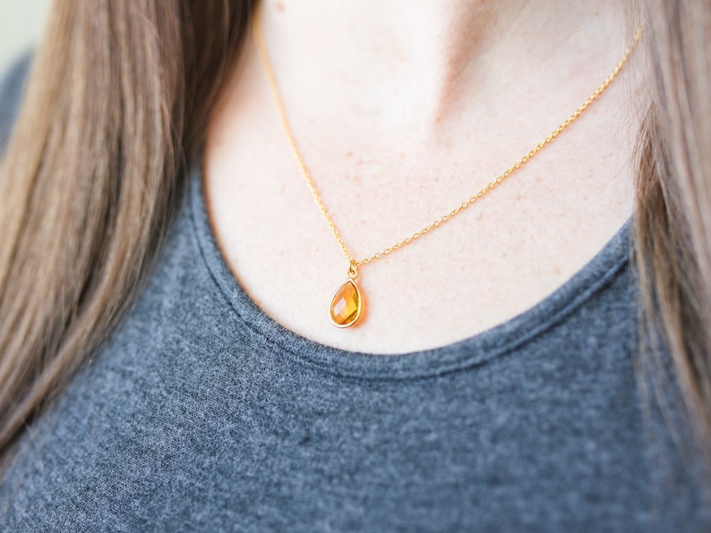 May include: A gold chain necklace with a teardrop-shaped amber pendant.