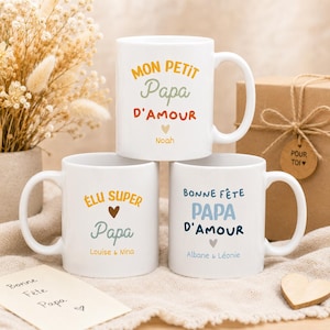 Peut inclure: Trois mugs en céramique blancs avec du texte coloré. Le mug du haut dit "MON PETIT Papa D'AMOUR Noah". Le mug du milieu dit "ÉLU SUPER Papa Louise & Nina". Le mug du bas dit "BONNE FÊTE Papa D'AMOUR Albane & Léonie".