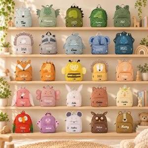 Peut inclure: Une collection de vingt-cinq petits sacs à dos sur le thème des animaux, disposés sur cinq étagères en bois. Chaque sac à dos présente un design de personnage unique, comme un ours, un dinosaure, un requin ou un hibou, avec un nom personnalisé.