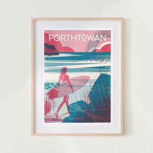 Può includere: Stampa artistica incorniciata raffigurante un surfista che cammina verso l'oceano con una tavola da surf. La stampa ha uno stile retrò con il testo "Porthtowan Cornwall" in rosso e bianco. L'opera è incorniciata in una cornice di legno chiaro.
