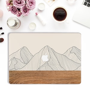 May include: A beige laptop skin with a black line drawing of mountains. The bottom of the skin is a wood grain pattern.