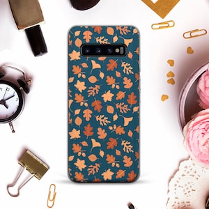 May include: A clear phone case with a blue background and a pattern of orange and brown leaves. The case is designed for a Samsung Galaxy S10.
