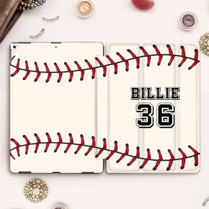 May include: A white iPad case with a baseball stitching design and the name "Billie" and the number "36" in black.