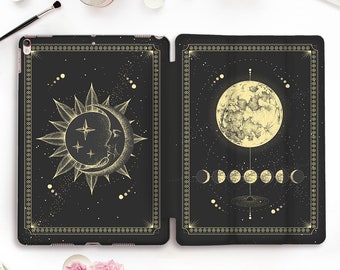 May include: A black iPad case with a gold design of the sun and moon. The sun is depicted with a crescent moon inside of it. The moon is depicted with a full moon and phases of the moon.
