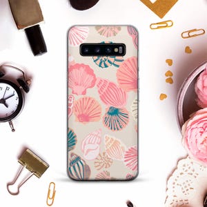 May include: A phone case featuring a beige backdrop adorned with pink, peach, and teal seashell designs. The case is designed for a Samsung Galaxy S10.