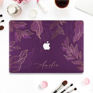 May include: Purple laptop case with a gold floral design and the name "Amelia" printed on the front.