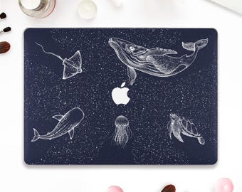 May include: A navy blue laptop case featuring a white illustration of marine life, including a whale, stingray, shark, jellyfish, and sea turtle. The design includes a white Apple logo and a speckled background.