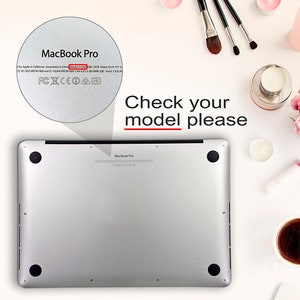 以下が含まれることがあります： シルバーのMacBook Proラップトップの背面のクローズアップ。ラップトップには、モデル番号A1500、EMC 2678、シリアル番号CO2LKが背面に印刷されています。テキスト「モデルを確認してください」は、白地に赤と黒で書かれています。