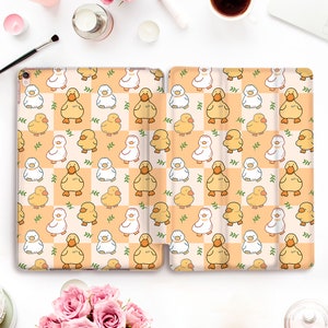 May include: A white and orange iPad case with a repeating pattern of yellow ducklings and green leaves on a checkered background.