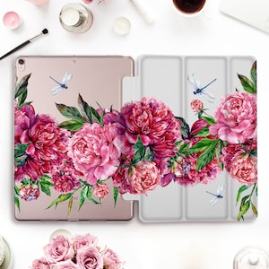 May include: A clear case for an iPad with a floral design. The case features pink peonies and green leaves with blue dragonflies. The case is made of a durable material and is designed to protect your iPad from scratches and bumps.