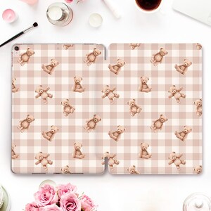 Könnte beinhalten: Eine Tablet-Hülle mit einem hellbraunen und weißen Vichy-Muster, verziert mit einem sich wiederholenden Muster von Aquarell-Teddybären. Die Bären sind in verschiedenen Posen dargestellt. Die Hülle ist geöffnet und zeigt das Innendesign. Das Design wirkt weich und verspielt.