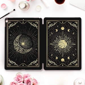 Könnte beinhalten: Schwarze Tablet-Hülle mit einem goldenen Himmelsdesign mit einem Halbmond und einer Sonne mit Strahlen. Die Hülle ist geöffnet und gibt den Blick auf das Innere frei. Das Design ist mit dekorativen Bordüren umrahmt.