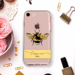 May include: A clear phone case with a yellow and black bee with flowers on its head. The case has a yellow band with the name "Jessica SMITH" written in black.
