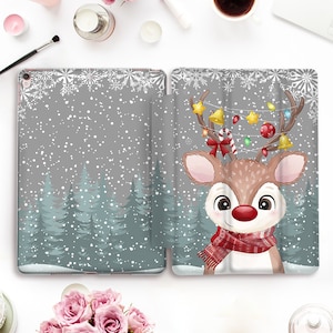 May include: A gray and white iPad case with a cute cartoon reindeer wearing a red scarf and a Christmas hat. The reindeer is surrounded by a snowy forest scene with snowflakes.