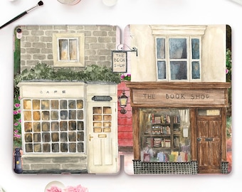 May include: A watercolor illustration of two shops side-by-side. The shop on the left is a cafe with a sign that says "Cafe". The shop on the right is a bookstore with a sign that says "The Book Shop".