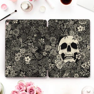 May include: A black and white iPad case with a floral pattern and a skull in the center. The skull is surrounded by flowers and leaves.