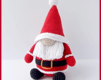 May include: A crocheted Santa Claus gnome doll. The doll has a red hat with a white pom-pom, a white beard, and a red suit with a black belt. The gnome's shoes are black. The doll is a festive decoration.