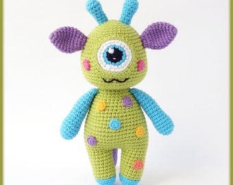 May include: A green crocheted monster toy with one large eye, purple ears, and colorful polka dots.