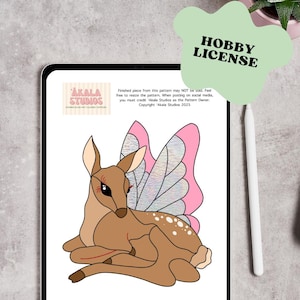 May include: A digital illustration of a fawn with butterfly wings, displayed on a tablet. The fawn is brown with white spots and pink and iridescent wings. The tablet displays the text "Akala Studios" and "Hobby License."