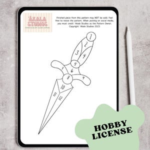 May include: A digital tablet displays a black and white stained glass pattern of a dagger, numbered for assembly. The tablet also shows the Akala Studios logo and text about the pattern's usage. A green "HOBBY LICENSE" sticker is in the foreground.