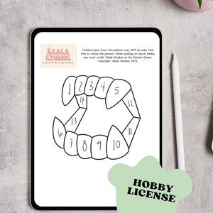 May include: A digital tablet shows a black and white pattern of vampire teeth, numbered 1-14. The Akala Studios logo is in the upper left. Text on the screen states the pattern is for personal use only. A green "Hobby License" sticker is in the lower right.
