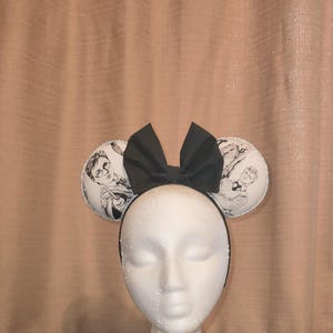 May include: Black and white mouse ears with a black bow. The ears feature a printed image of a person with glasses and a wand.
