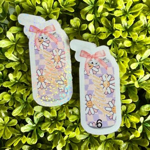 Pode incluir: Dois autocolantes em forma de copo de ch&aacute; gelado, com um la&ccedil;o rosa. Apresentam um fundo xadrez, flores de margarida sorridentes e a palavra "happy" em it&aacute;lico. O n&uacute;mero "6" &eacute; vis&iacute;vel no canto inferior direito.