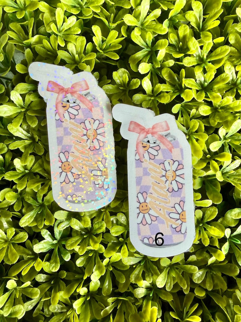 Pode incluir: Dois autocolantes em forma de copo de ch&aacute; gelado, com um la&ccedil;o rosa. Apresentam um fundo xadrez, flores de margarida sorridentes e a palavra "happy" em it&aacute;lico. O n&uacute;mero "6" &eacute; vis&iacute;vel no canto inferior direito.