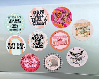 May include: A collection of ten circular stickers featuring various designs and text including If You See Me Hit The Curb Mind Your Business, Oops Was That A Curb, Probably Late, Stars Hollow, But Did You Die, Will Brake For Yard Sales, Better Late Than Uncaffeinated, Don't Let Idiots Ruin Your Day, Cute But Trashy with an opossum, and My Book Boyfriends Have Wings.