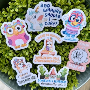 May include: A collection of colorful stickers featuring cartoon characters and humorous phrases. The stickers include an owl, a unicorn, and various dog-like characters. Phrases include "and WHHHHY SHOULD I care?" and "That's great, babe."