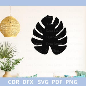 May include: A black silhouette of a Monstera leaf, a common tropical plant, is shown against a white backdrop. The image includes the text "CDR DFX SVG PDF PNG". This design is suitable for crafting projects and home decor.