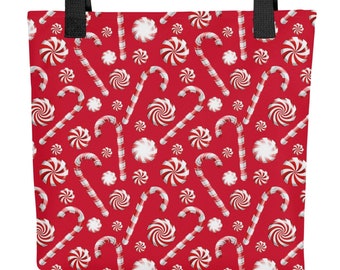 May include: A red tote bag with a repeating pattern of white and red candy canes and peppermint candies. The bag has black handles and is designed for carrying items.