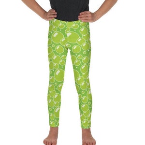 May include: Green leggings with a white bubble pattern. The leggings are on a young person.