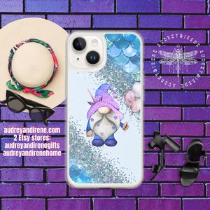 May include: Clear phone case featuring a whimsical gnome with a unicorn horn, holding balloons. The design includes blue glitter and mermaid scale accents. The case is set against a light blue background. Text on the case reads: audreyandirene.com, 2 Etsy stores: audreyandirenegifts, audreyandirenehome.