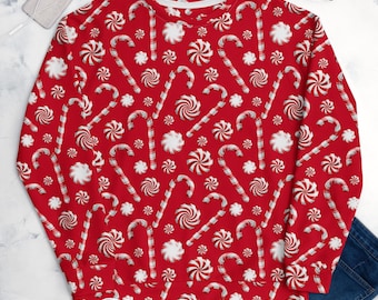 May include: A red long-sleeve sweatshirt featuring an all-over repeating pattern of white and red striped candy canes and round peppermint swirl candies. The garment has a crew neckline and ribbed cuffs, providing a festive holiday design.