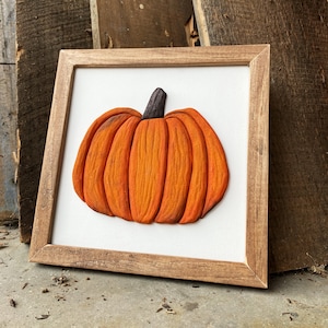 May include: A wooden framed wall art piece featuring a 3D carved pumpkin with an orange and brown color scheme.