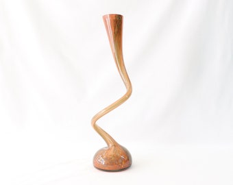 Op de afbeelding: Een hoge, gedraaide glazen vaas met een bolvormige basis. De vaas is gemaakt van helder glas met een draaiende patroon van bruin en oranje.