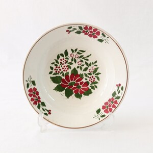 May include: White oval ceramic bowl with a floral design. The bowl has a red and green floral pattern with a gold rim.