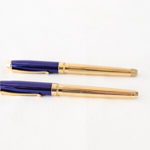 May include: A set of two gold and blue pens. The pens have a gold trim and a blue barrel.